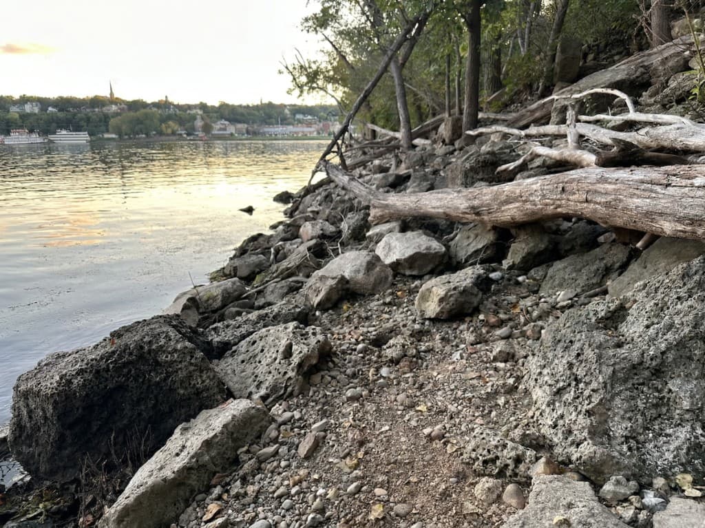 Rocky riverbank along the St. Croix with Stillwater visible across the water at golden hour